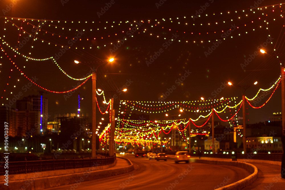 the dam and the road on it with passing cars at the new year's illumination, filmed on a December evening in Cheboksary