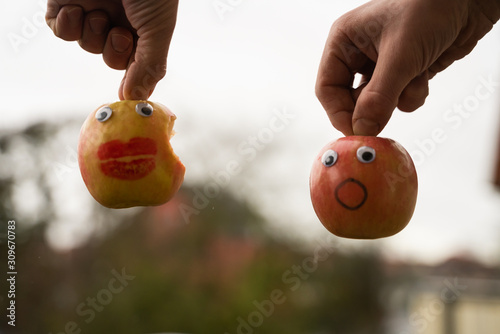 ein Apfel mit einem entsetzten gesicht sieht wie seine freundin angebissen wurde photo