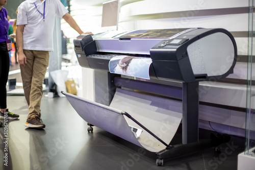 plotter prints a poster. standing next to people in blur. close-up, background in blur