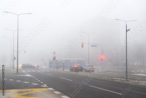 City crossroads with stoplights and pedestrians in the fog