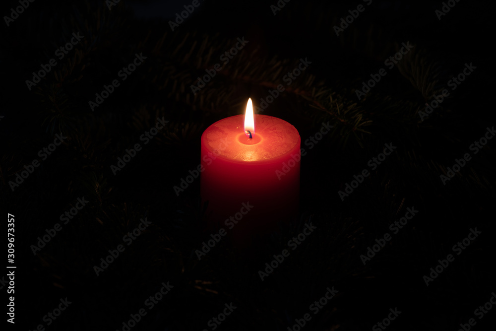 Christmas motif with red burning candle and dark background Christmas motif with red burning candle and dark background