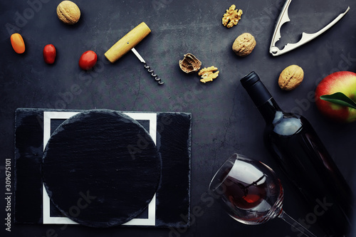 Wine glass and black wine bottle. Nuts cheese and tomatoes for snack.