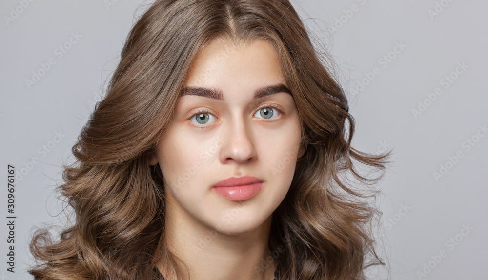Portrait of a beautiful happy woman with curly hair, clean skin and thick eyebrows beauty salon. Eyelash extensions. Face close-up. Make-up concept. Portrait of a beautiful happy woman with curly hair, clean skin and thick eyebrows beauty salon. Eyelash extensions. Face close-up. Make-up concept.