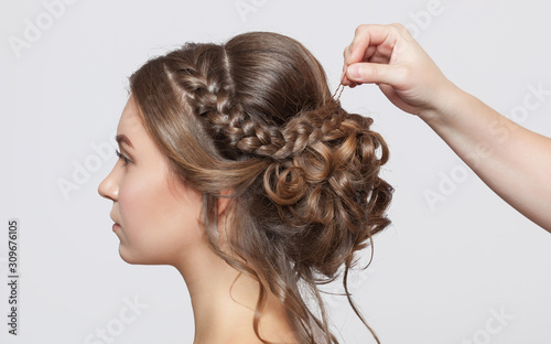 Portrait of a beautiful sensual light brown haired woman with a wedding hairstyle in a beauty salon. The hairdresser does the hairstyle. Wedding hairstyle. photo