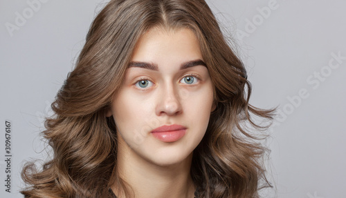 Portrait of a beautiful happy woman with curly hair, clean skin and thick eyebrows  beauty salon. Eyelash extensions. Face close-up. Make-up concept.