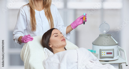 Cosmetologist does prp therapy on the face and scalp of a beautiful, young woman with clean skin in a beauty salon. There is in vitro  blood plasma, ready for injection. Cosmetology concept. photo