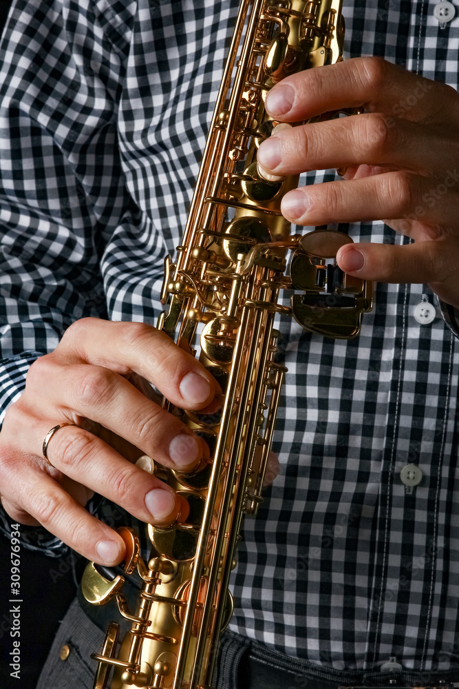 Fototapeta premium soprano saxophone in hands on a black background