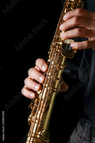 soprano saxophone in hands on a black background