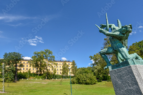 The statue in the Frihetens Port in Djurgarden island in Center of Stockholm. The building of Manillaskolan school is at background. photo