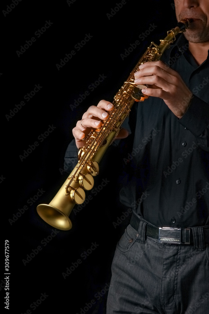 Naklejka premium soprano saxophone in hands on a black background