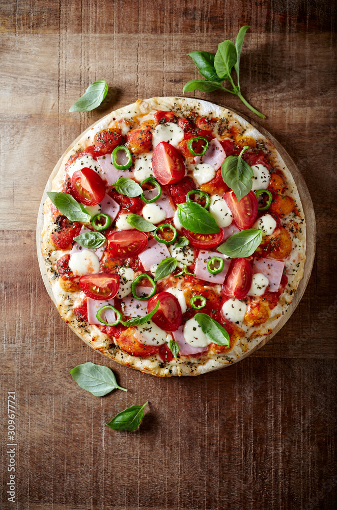 Pizza with ham, cherry tomatoes, mozzarella cheese, jalapeno pepper and fresh herbs. 