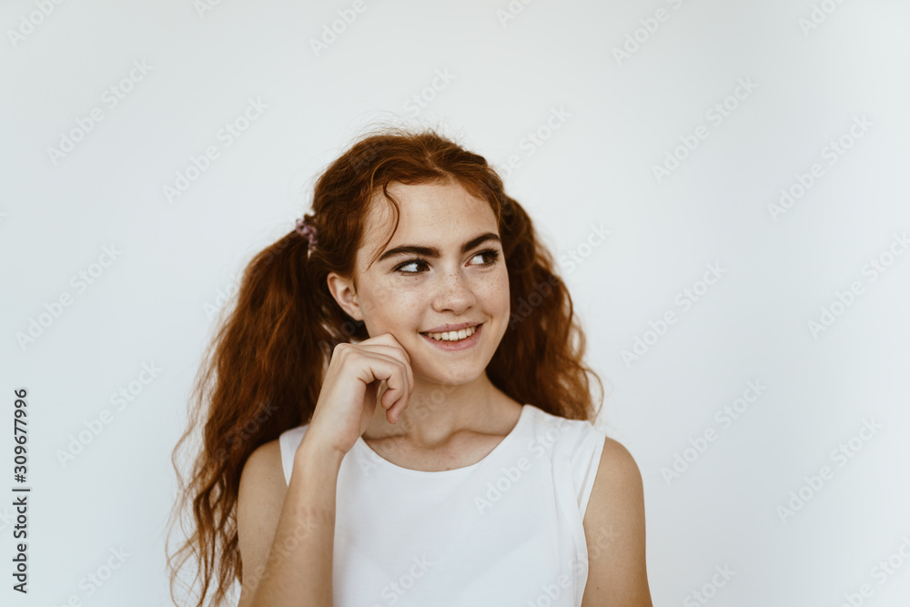 a cunning and mischievous look of a girl with tails of red very thick and long hair. gray background a cunning and mischievous look of a girl with tails of red very thick and long hair. gray background