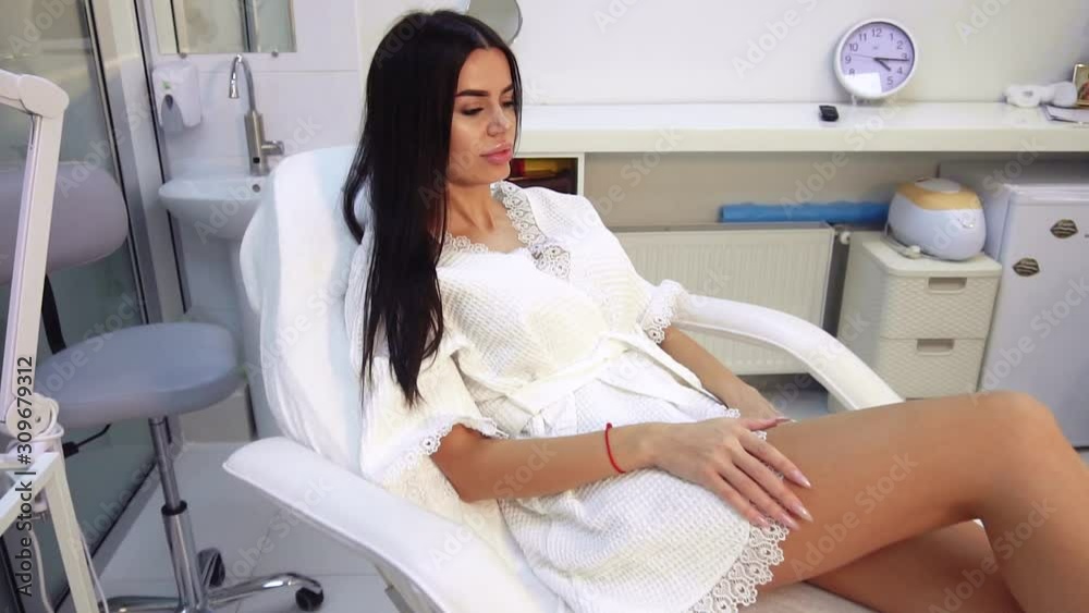 Beautiful girl in a beauty salon alone on a couch admires her body Beautiful girl in a beauty salon alone on a couch admires her body