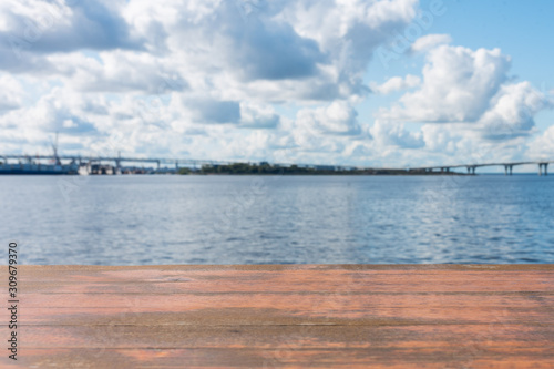 Template. Photo of an empty surface on a background of water and sky with clouds.