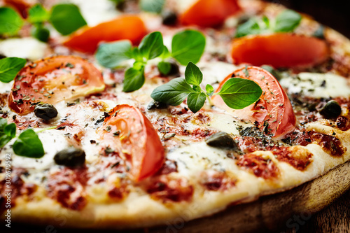 Vegetarian pizza with mozzarella cheese, tomatoes and capers.  Close up. 