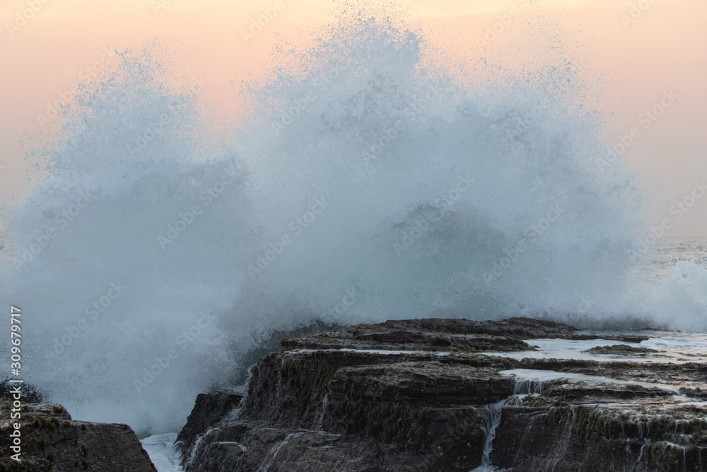 Big wave crashing into the rock on the coastline.