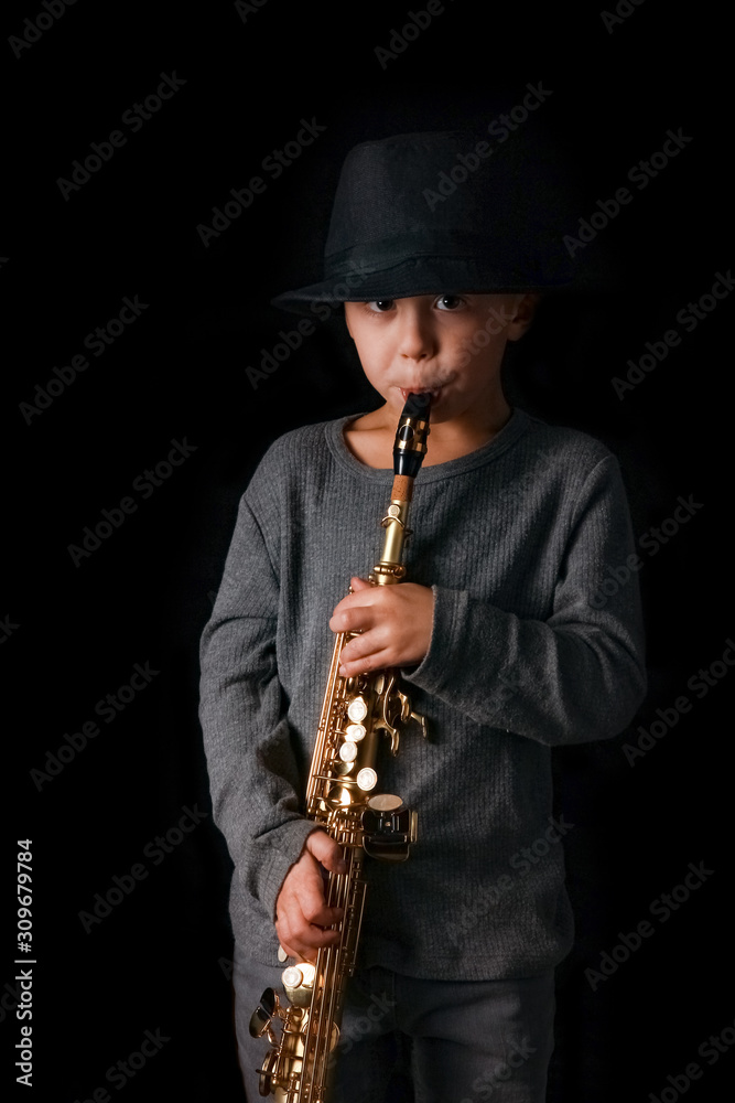 Fototapeta premium happy child plays saxophone in studio