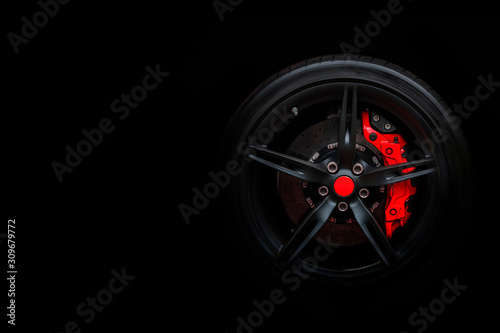 Isolated generic sport car wheel with red breaks drifting and smoking on a black background