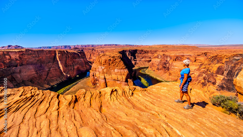 Senior Woman looking over the edge of the Horseshoe Bend Canyon of the Colorado River near Page, Arizona, United States