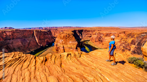 Senior Woman looking over the edge of the Horseshoe Bend Canyon of the Colorado River near Page, Arizona, United States