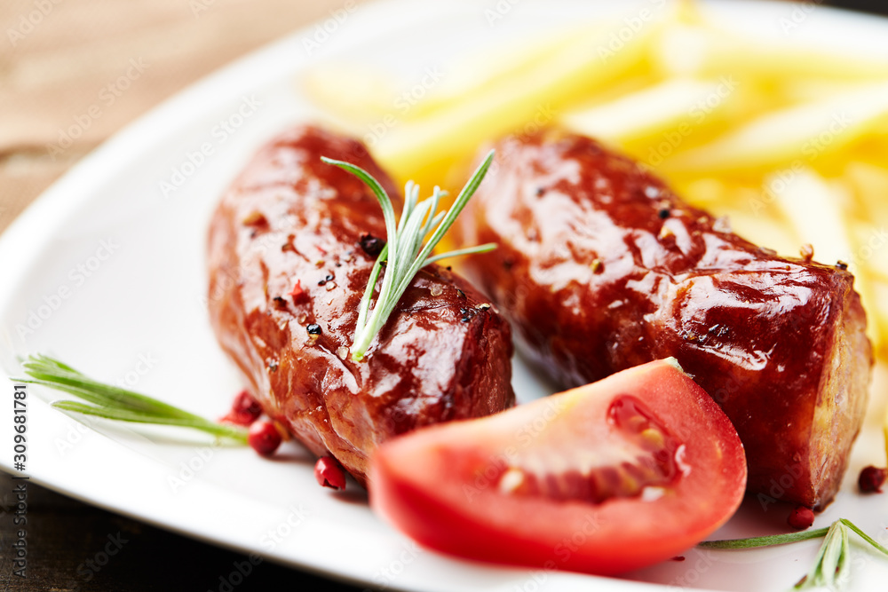 Roasted sausages with tomatoes and french fries, Close up. 