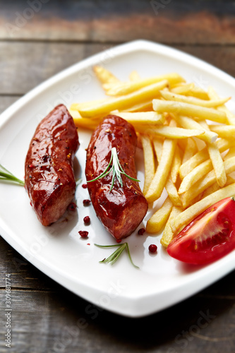 Roasted sausages with tomatoes and french fries, Close up.