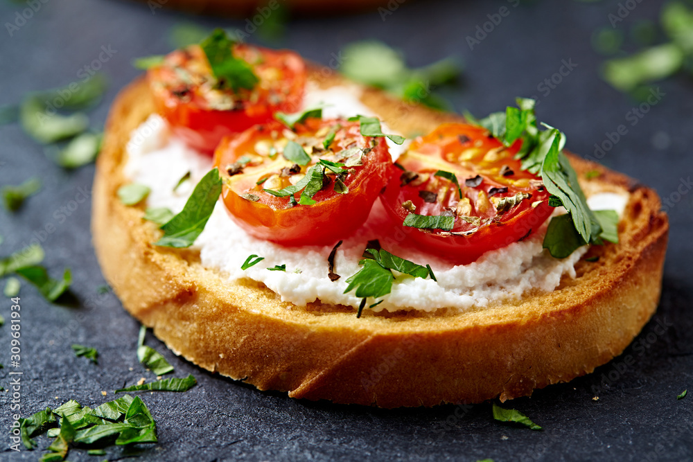 Crostini withe cream cheese, cherry tomatoes and fresh basil. Dark stone background. Close up. Crostini withe cream cheese, cherry tomatoes and fresh basil. Dark stone background. Close up.