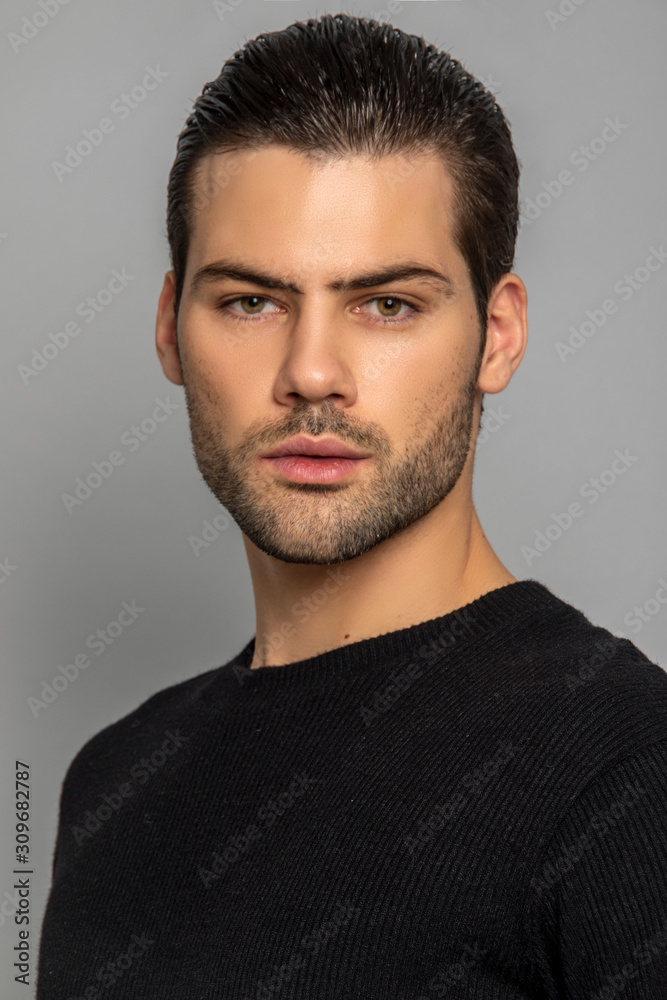Muscle strong beautiful stripped male model in black jamper and black trousers on grey isolated font background Muscle strong beautiful stripped male model in black jamper and black trousers on grey isolated font background