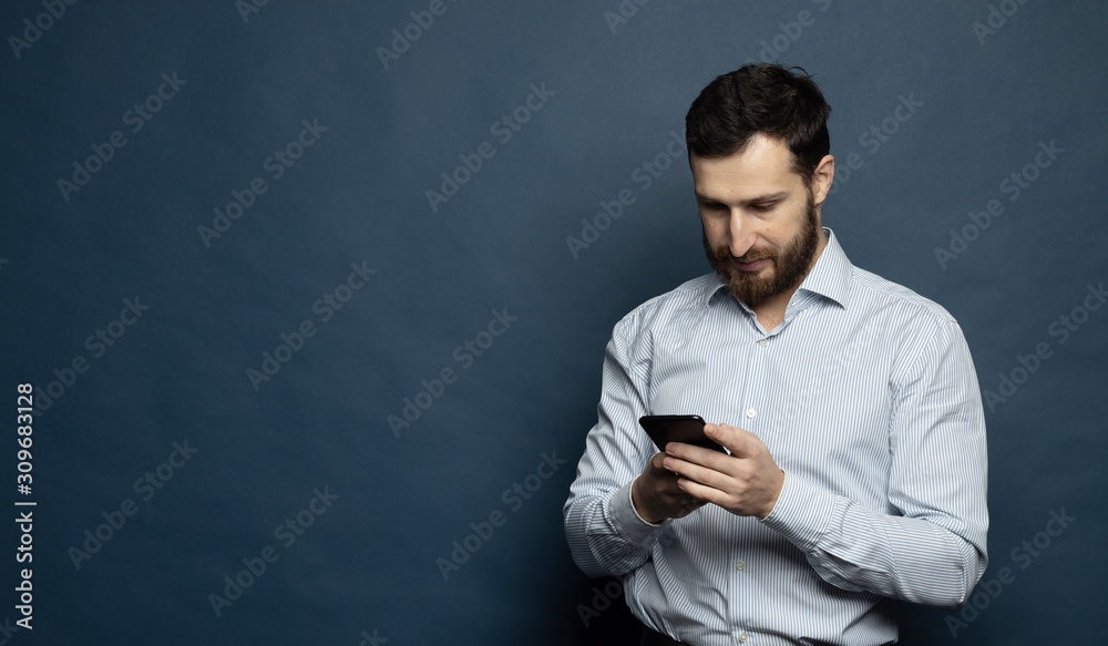 Happy bearded businessman using smartphone over blue background