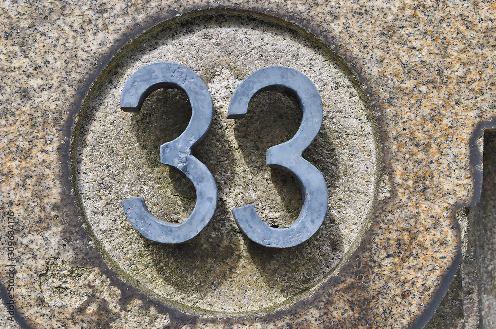 A house number plaque, showing the number thirty three (33)