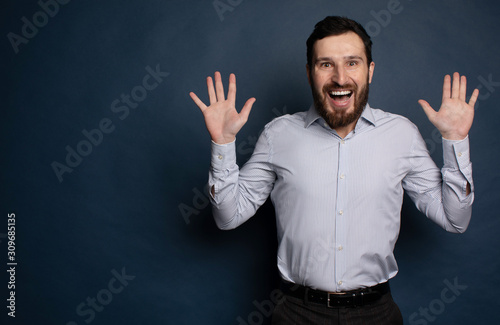 Happy bearded businessman looking at camera on blue background with copy space.