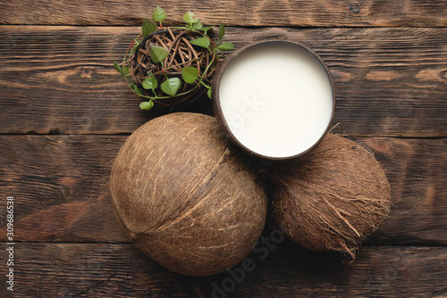 Coconut milk in cup and coconut on brown wooden table background.