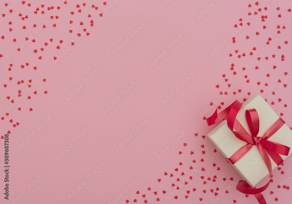 Valentine's Day concept. White gift box with red ribbon on pink background with lots of small red hearts. Valentine greeting card. Flat lay style with copy space.