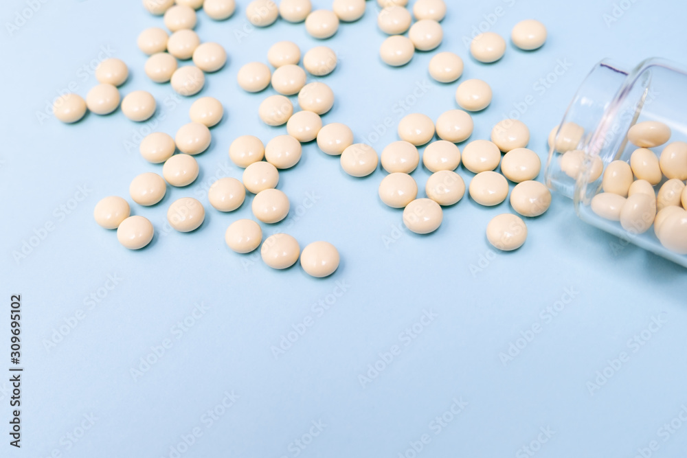 Fighting against cancer, tablets for chemotherapy in glass transparent bottle on blue background, copy space