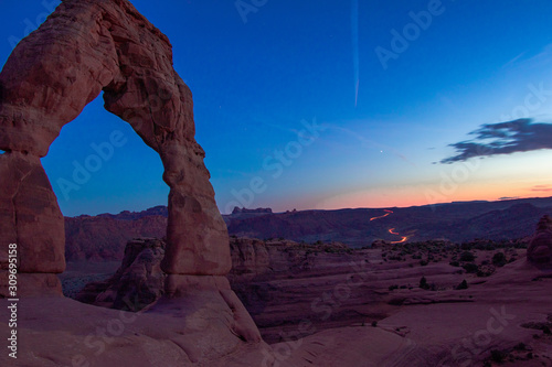 Delicate Arch with cars exiting the park in the background © Mark Widder