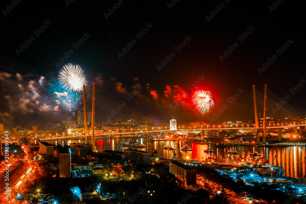 Fireworks in Vladivostok. Salute in honor of Victory Day in Vladivostok against the backdrop of the Golden Bridge and the central part of the city.