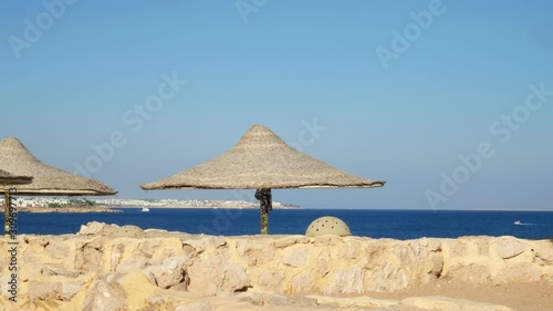 Beach umbrella on coastline with waves in sea with blue water and nocloud sky background photo