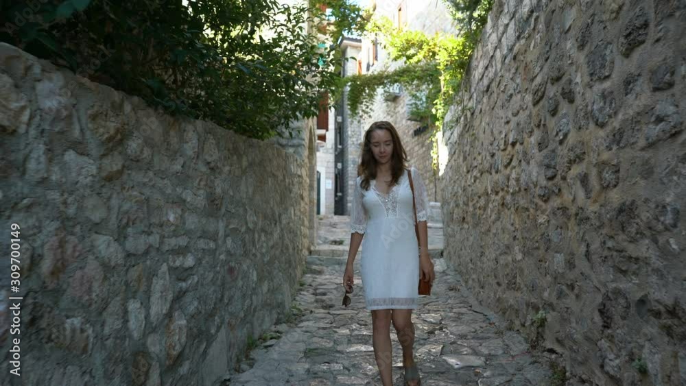 young woman walks the streets of the old city of Ulcinj young woman walks the streets of the old city of Ulcinj