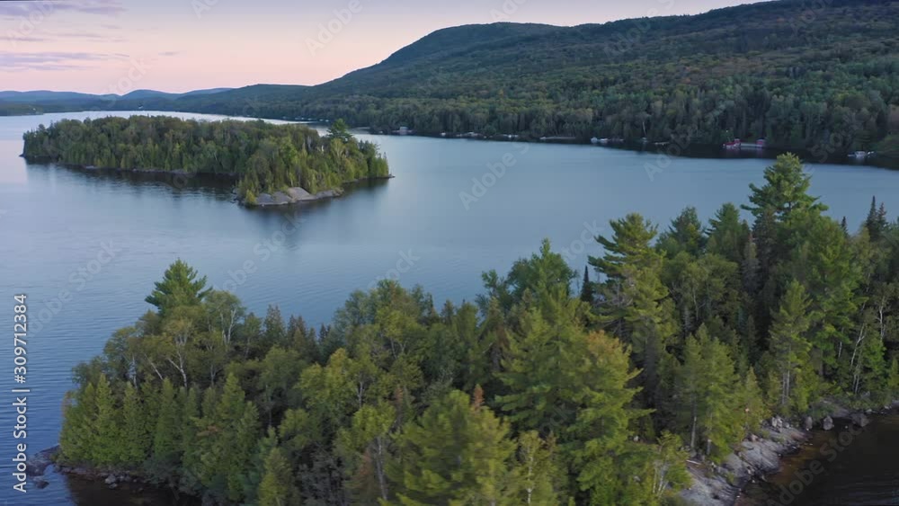 Aerial: Forest & calm tranquil Ouareau Lake at sunset. Islands are scattered throughout the lake. Laurentian Mountains near Montreal, Quebec, Canada Aerial: Forest & calm tranquil Ouareau Lake at sunset. Islands are scattered throughout the lake. Laurentian Mountains near Montreal, Quebec, Canada
