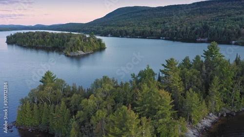 Aerial: Forest & calm tranquil Ouareau Lake at sunset. Islands are scattered throughout the lake. Laurentian Mountains near Montreal, Quebec, Canada photo