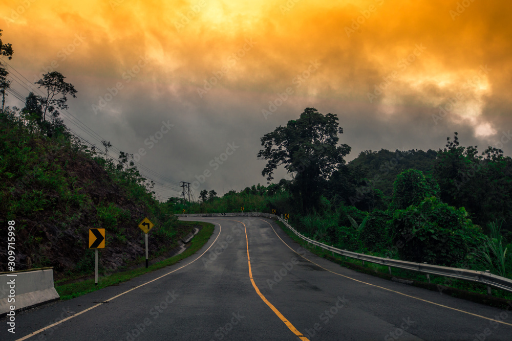 Blurred background of a mountain road view, from a car windscreen that runs with care, with natural scenery surrounded by plants, large trees Blurred background of a mountain road view, from a car windscreen that runs with care, with natural scenery surrounded by plants, large trees