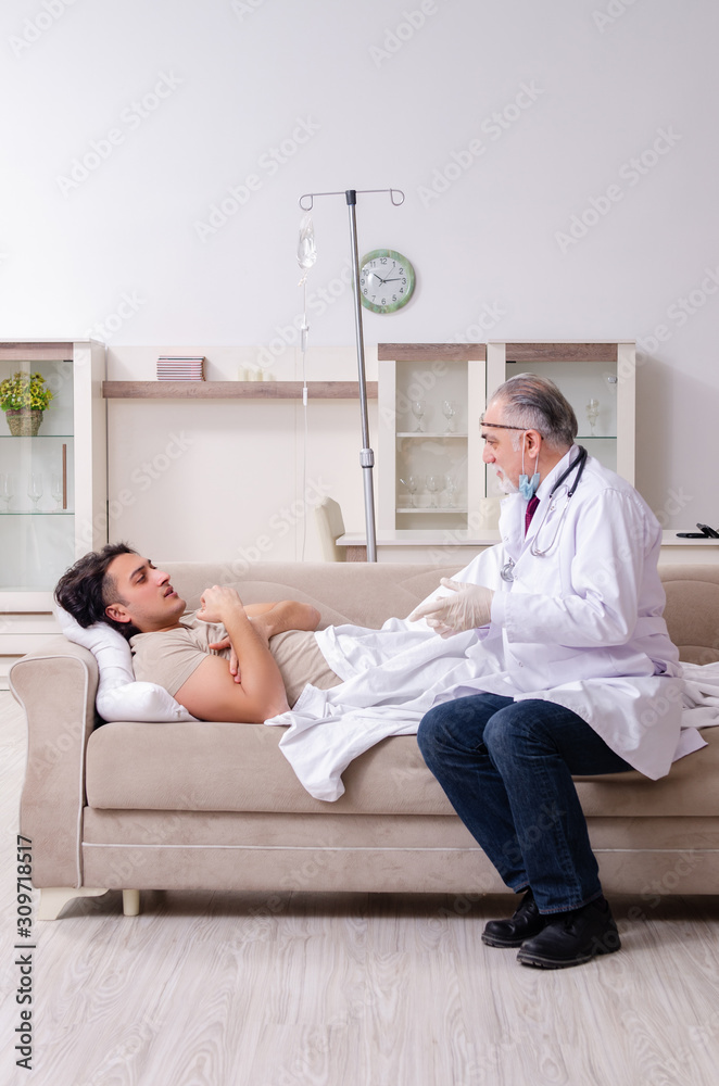 Obraz premium Old male doctor visiting young male patient