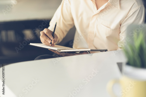 Wallpaper Mural Close up of male hand writing with pencil on the book. Businessman working with data information in the office. Torontodigital.ca