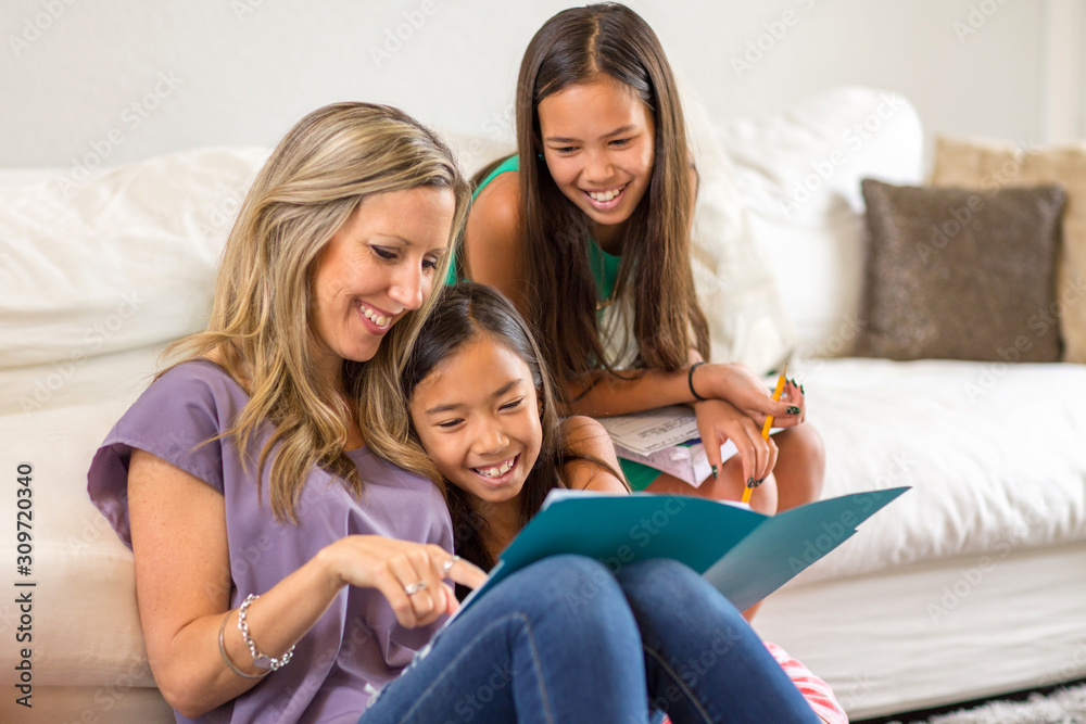 Mother Reading To Her Daughters And Helping Them With Their Homework Mother Reading To Her Daughters And Helping Them With Their Homework
