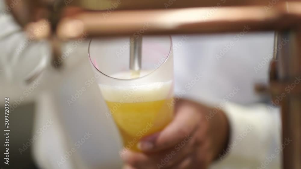 copper beer dispenser with blurred bartender poured cold draft beer into glass, selective focus