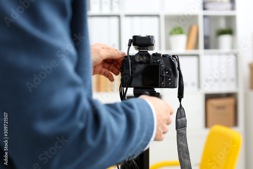 Male arms in suit mount camcorder to tripod