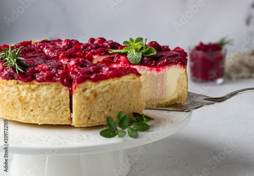 Classical New York cheesecake with cranberry sauce  mint and rosemary  light grey stone background. 