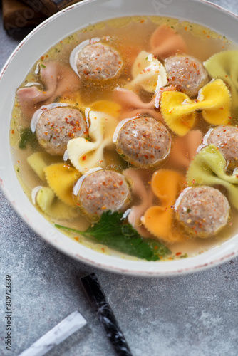 Close-up of meatball soup with farfalle pasta, vertical shot, selective focus