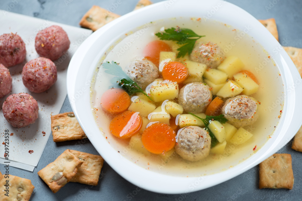 Close-up of soup with meatballs, potato, carrot and parsley served in a white plate, studio shot Close-up of soup with meatballs, potato, carrot and parsley served in a white plate, studio shot