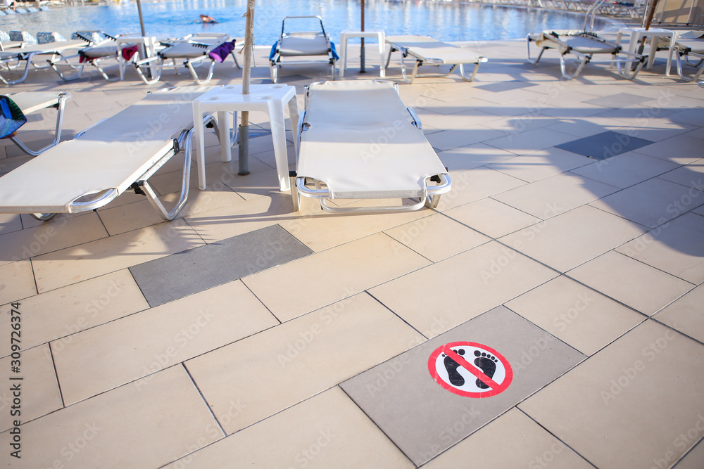 Obraz premium No walking or running barefoot sign on a hotel swimming pool